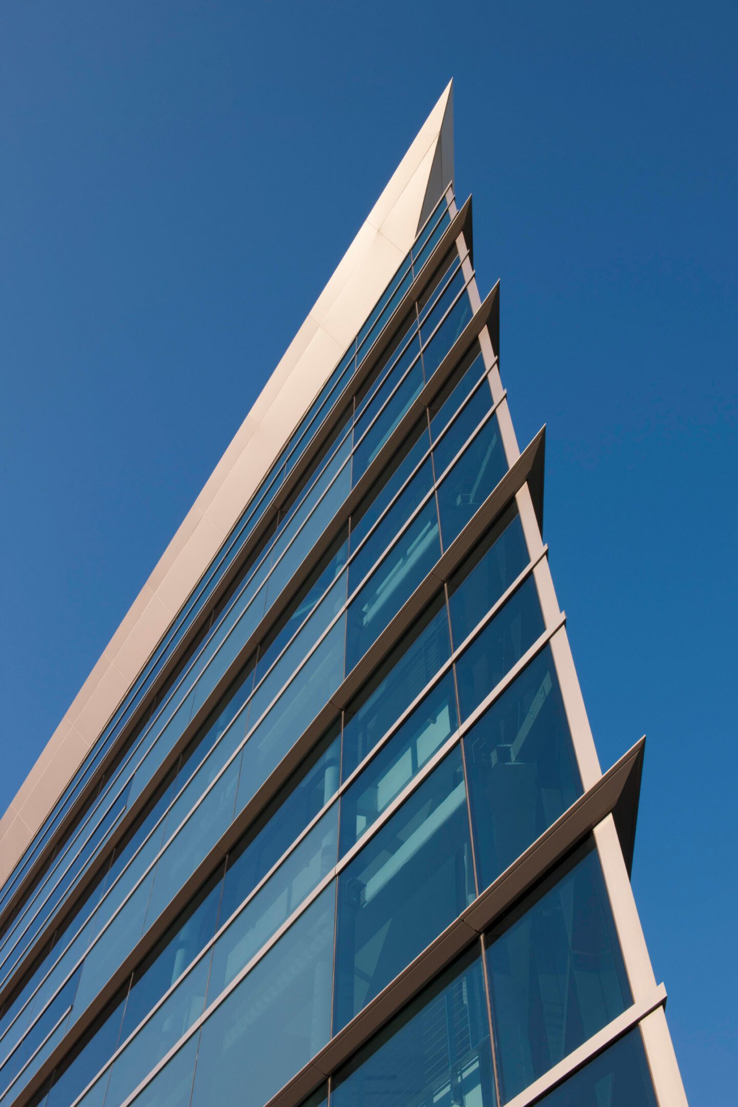 Modern glass building against clear blue sky.