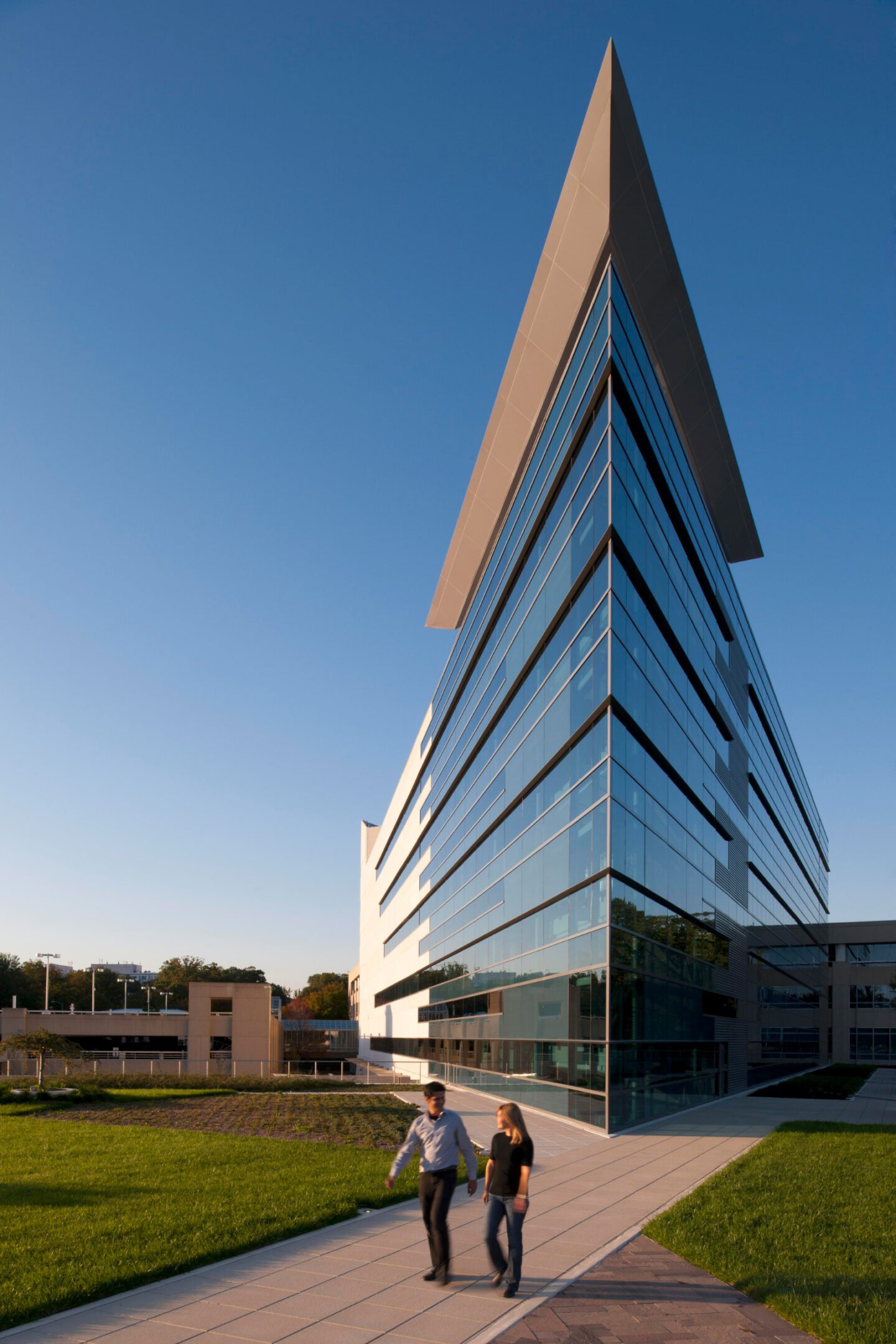 Modern glass building with two people outside.
